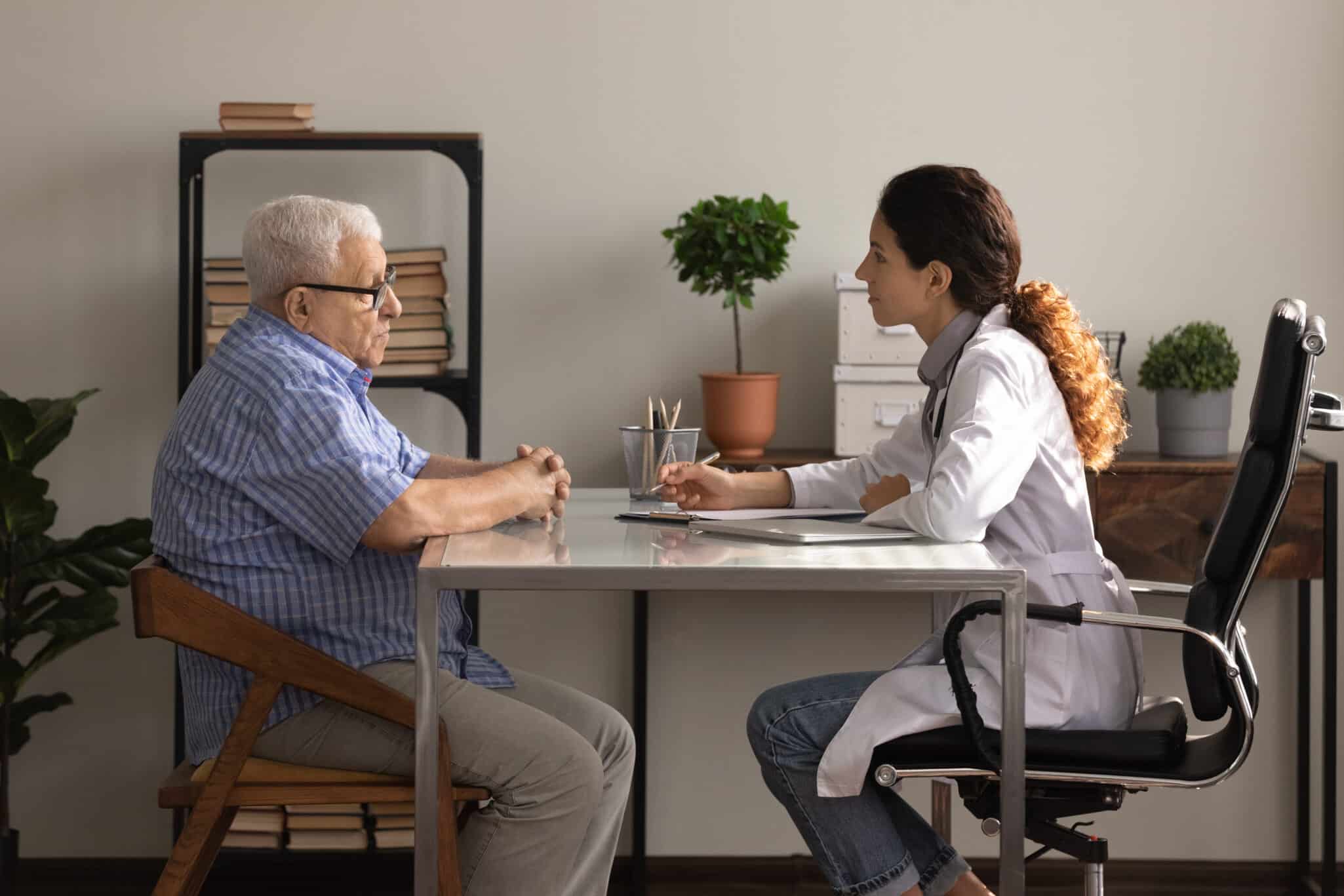 Older man patient meeting woman attending physician for medical checkup